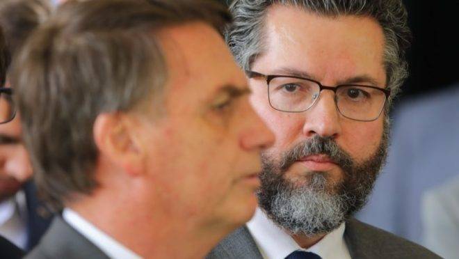 O ministro das Relações Exteriores, Ernesto Araújo, olha para o presidente Jair Bolsonaro