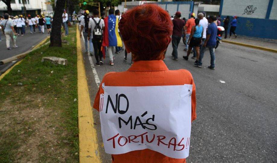 Mulher com cartaz que diz "Não mais tortura" participa de marcha contra o regime de Maduro em Caracas, 5 de julho