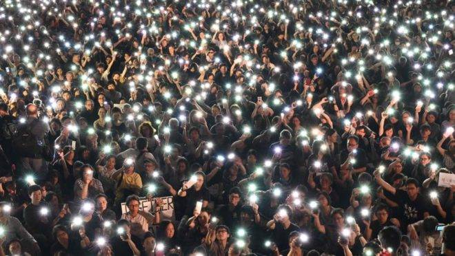 Manifestantes seguram celulares durante marcha organizada por mães de Hong Kong em apoio aos manifestantes que protestam contra o projeto de lei que permitiria a extradição para a China