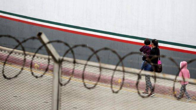 Uma migrante centro-americana e seus filhos em frente ao ponto de entrada em El Chaparral, em Tijuana, no estado mexicano de Baja California, em 17 de julho de 2019
