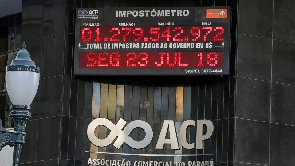 Vai sair do papel? Reforma tributária deve ter votação rápida Impostômetro na fachada da Associação Comercial do Paraná.