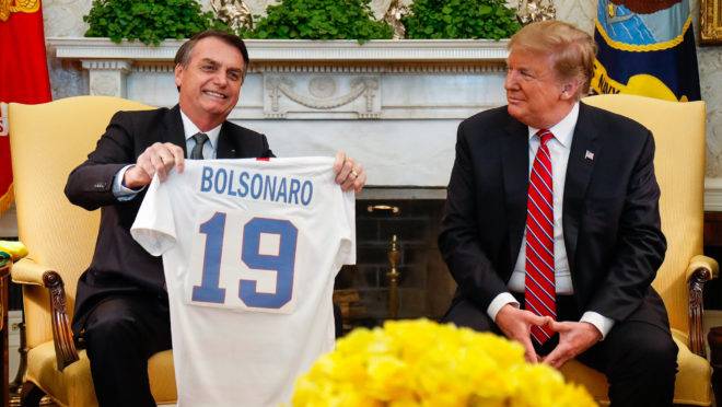 Donald Trump entrega camisa personalizada da seleção de futebol dos EUA com o nome de Bolsonaro.