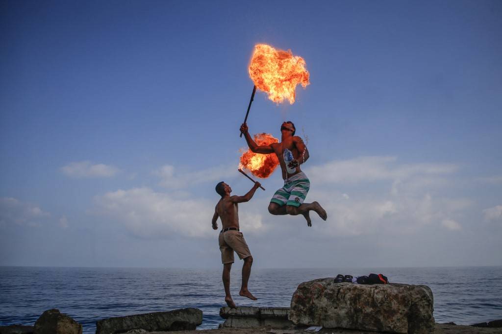Palestinos fazem uma apresentação com fogo para entreter visitantes da Cidade de Gaza durante as férias de verão. Palestinos fazem uma apresentação com fogo para entreter visitantes da Cidade de Gaza durante as férias de verão.