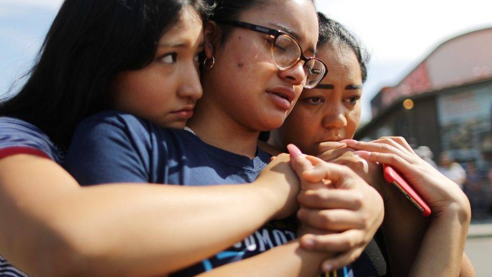 A mãe, Aidee Gutierrez (direita), de origem mexicana, e suas filhas Marlene Gutierrez e Brissa Martinez se abraçam em um memorial em frente ao Walmart em homenagem às vítimas de um massacre que deixou pelo menos 22 mortos, em El Paso, Texas (EUA), 5 de agosto