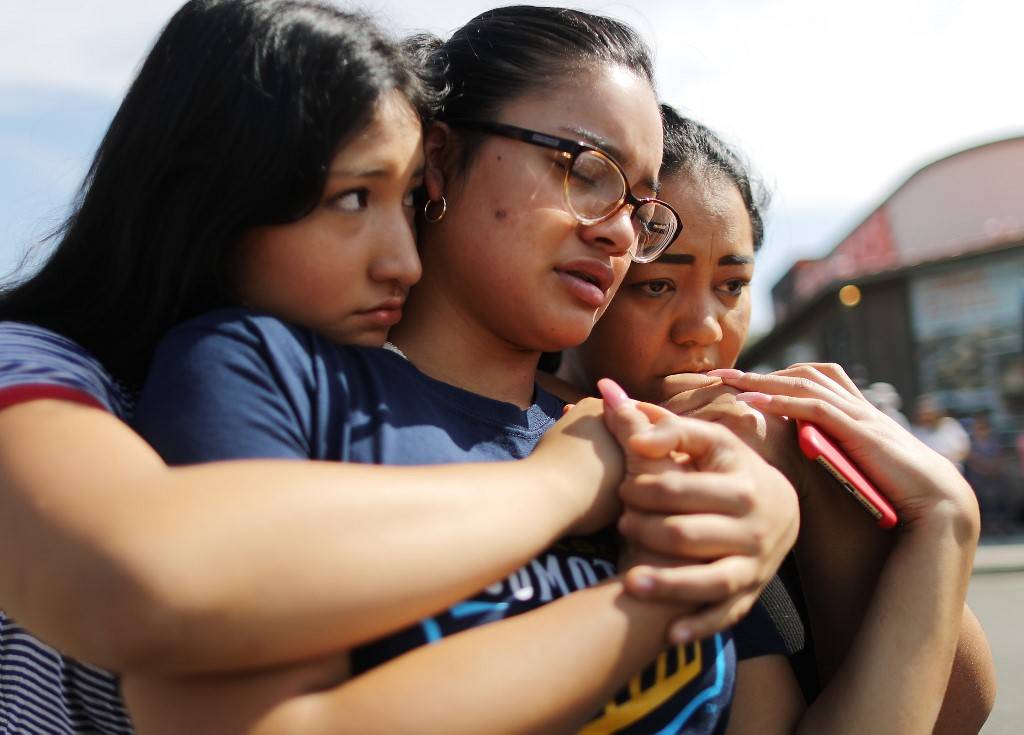 A mãe, Aidee Gutierrez (direita), de origem mexicana, e suas filhas Marlene Gutierrez e Brissa Martinez se abraçam em um memorial em frente ao Walmart em homenagem às vítimas de um massacre que deixou pelo menos 22 mortos, em El Paso, Texas (EUA), 5 de agosto