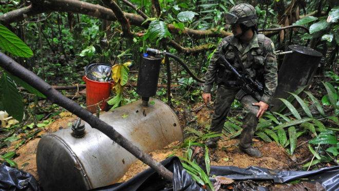 Soldado colombiano encontra tanque para armazenagem de cocaína em um laboratório de refino da Farc no meio da selva.