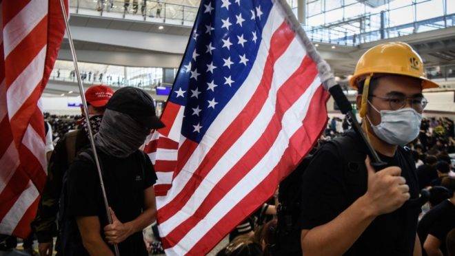 Manifestantes pró-democracia em Hong Kong levantam bandeiras dos Estados Unidos no aeroporto internacional da cidade.