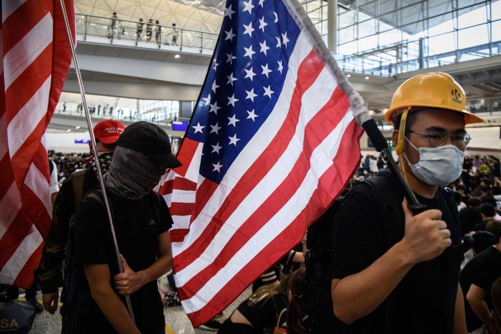 Manifestantes pró-democracia em Hong Kong levantam bandeiras dos Estados Unidos no aeroporto internacional da cidade.