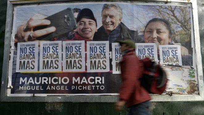 Outdoor de Mauricio Macri parcialmente coberto por cartazes com slogans contra o governo argentino, em Buenos Aires: atual presidente saiu derrotado das eleições primárias da Argentina.