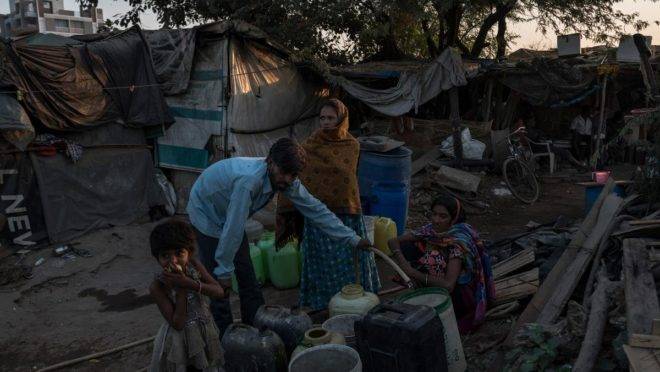 Moradores coletam água do lado de fora de uma barraca de chá em Ahmedabad, estado de Gujarat, Índia, em 24 de novembro de 2018 | REBECCA CONWAY/NYT