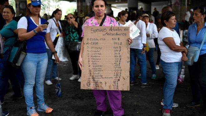 Uma enfermeira venezuelana segura um cartaz com a comparação de salários de enfermeiros na América Latina durante protesto por melhores salários e contra a falta de medicamentos e suprimentos em hospitais, em Caracas, 14 de agosto de 2019