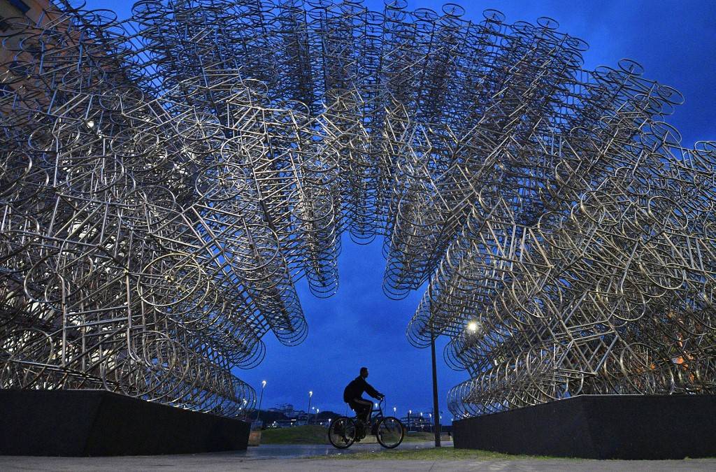 Homem passa de bicicleta pela instalação do artista chinês Ai Weiwei "Forever Bicycles", no Rio de Janeiro. A obra é composta por mais de mil bicicletas de aço e é parte da exposição do artista que será aberta no Rio nesta quarta-feira (22). Homem passa de bicicleta pela instalação do artista chinês Ai Weiwei "Forever Bicycles", no Rio de Janeiro. A obra é composta por mais de mil bicicletas de aço e é parte da exposição do artista que será aberta no Rio nesta quarta-feira (22).