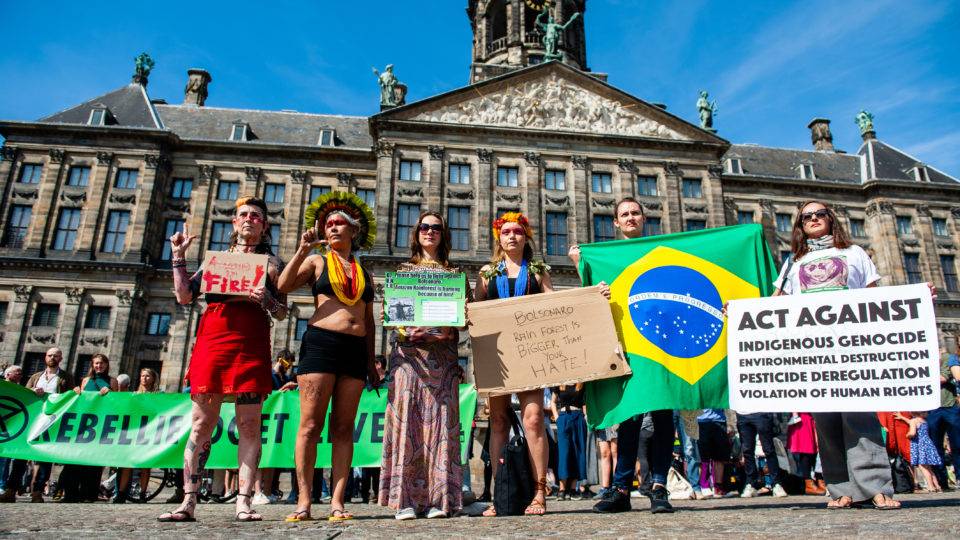 Manifestantes seguram cartazes contra políticas ambientais do governo brasileiro em Amsterdã, Holanda