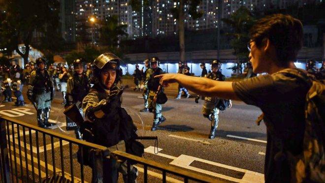 Manifestante e policial em confronto