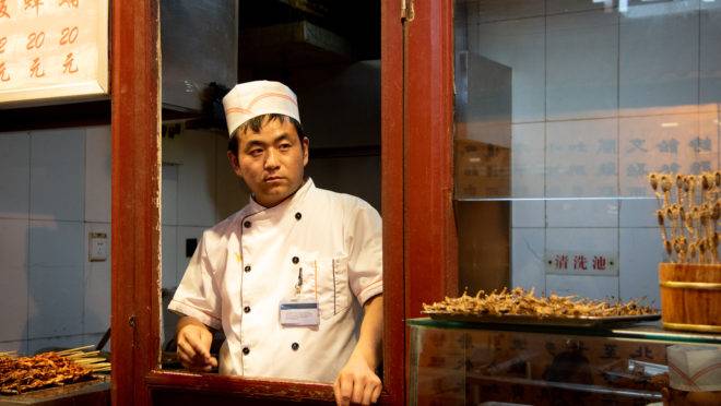 Chef chinês prepara alimentos típicos em mercado livre de Pequim