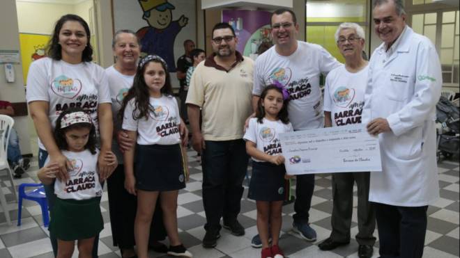 Manuela, que tratou um câncer no rim no Pequeno Príncipe, entrega cheque de R$ 16,2 mil ao diretor do hospital, Donizetti Giamberardino Filho.