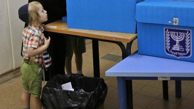 Criança observa homem preencher cédula durante a eleição parlamentar de Israel em Tel Aviv, 17 de setembro de 2019