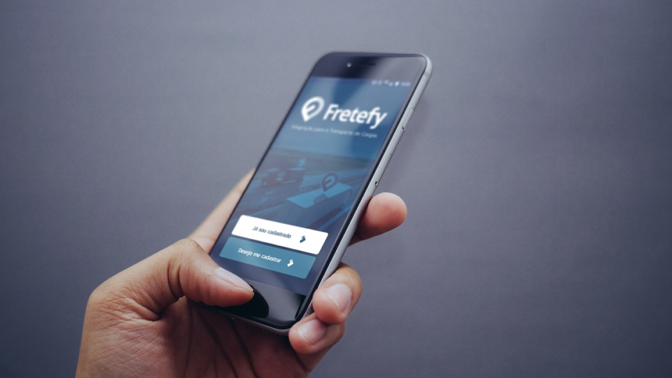 A imagem mostra um celular e o app da startup Fretefy