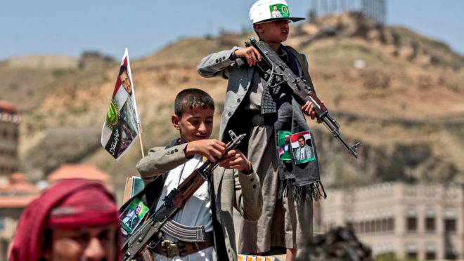 Garotos iemenitas seguram armas que lhes foram dadas pelos rebeldes houthis, no Iêmen