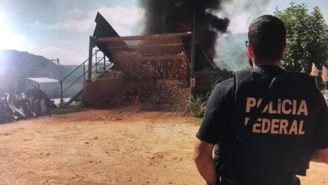 Policial federal observa incineração de drogas.