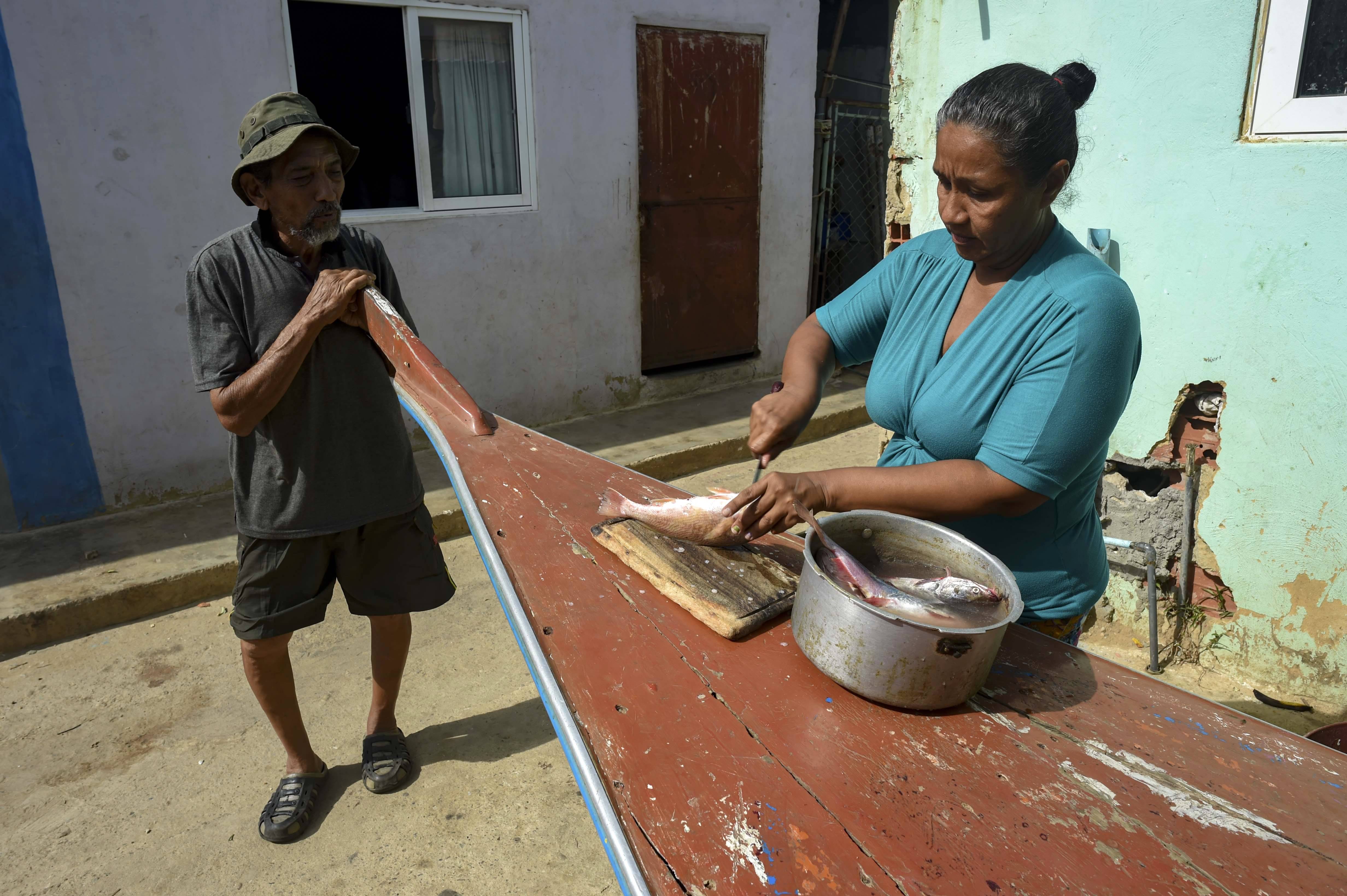 Uma mulher limpa um peixe extraído do poluído Lago Maracaibo | Foto: YURI CORTEZ / AFP Uma mulher limpa um peixe extraído do poluído Lago Maracaibo | Foto: YURI CORTEZ / AFP