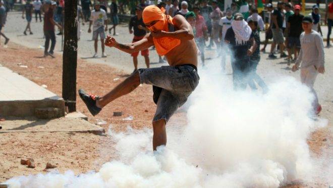 Apoiador do partido de Carlos Mesa, principal adversário de Evo Morales na eleição presidencial, chuta uma bomba de gás lacrimogêneo em confronto entre partidários dos dois candidatos em meio à disputa sobre resultados, Santa Cruz, Bolívia, 23 de outubro de 2019
