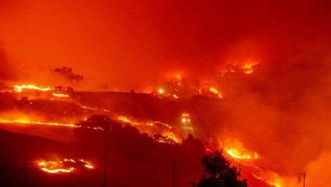 Caminhões de bombeiros trafegam por estradas cercadas de fogo durante o incêndio Kincade perto de Geyserville, no estado americano da Califórnia