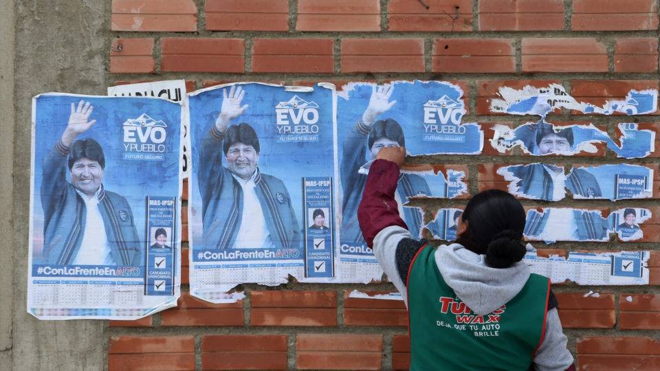 Mulher remove cartazes de Evo Morales, da Bolívia, da parede de uma casa em El Alto