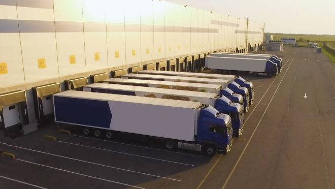 Caminhões estacionados em frente a um depósito aguardando carregamento