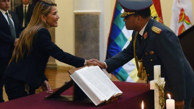 A presidente interina da Bolívia, Jeanine Áñez, cumprimenta o novo comandante das forças armadas, general Carlos Orellana, no palácio presidencial Quemado, em La Paz, 13 de novembro de 2019