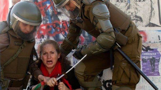Policiais detêm manifestante durante protesto em Santiago, na sexta-feira (15).