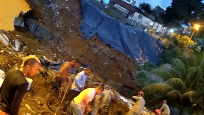 Pessoas trabalham no resgate de vítimas em área com casas destruídas.