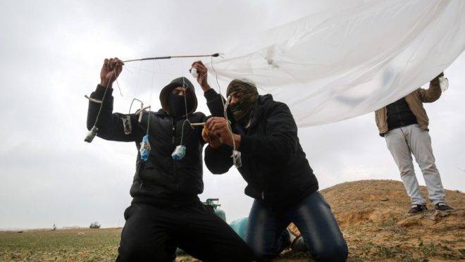 Jovens palestinos mascarados preparam objeto inflamável para ser atirado em território de Israel, perto da fronteira entre Gaza e Israel, 18 de janeiro de 2020