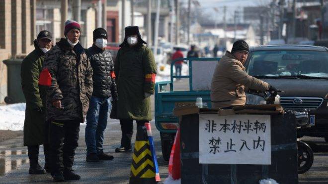 Moradores perto de bloqueio na entrada de sua vila para impedir propagação do coronavírus, em Jiuduhe, China, 7 de fevereiro de 2020