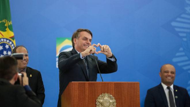 Jair Bolsonaro faz gesto de coração com as mãos em solenidade em 20 de fevereiro de 2020. Lançamento de crédito imobiliário com taxa fixa da Caixa