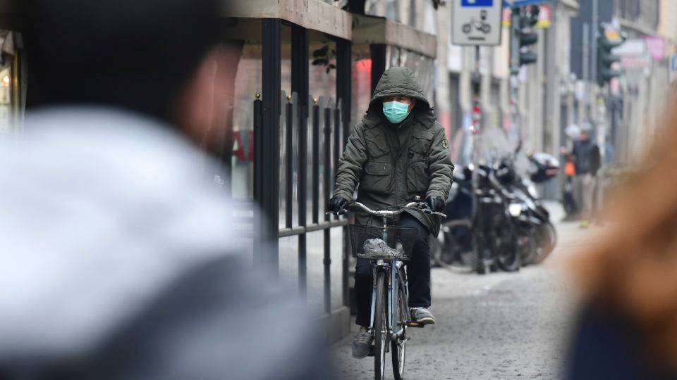 Um homem de máscara respiratória anda de bicicleta em uma rua do distrito chinês de Milão em 25 de fevereiro de 2020.