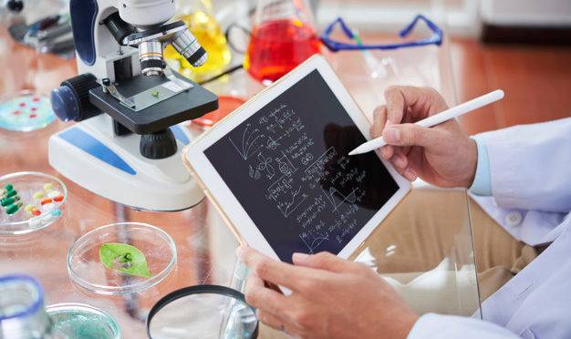 Scientist drawing chemical formulas and making calculations on tablet computer