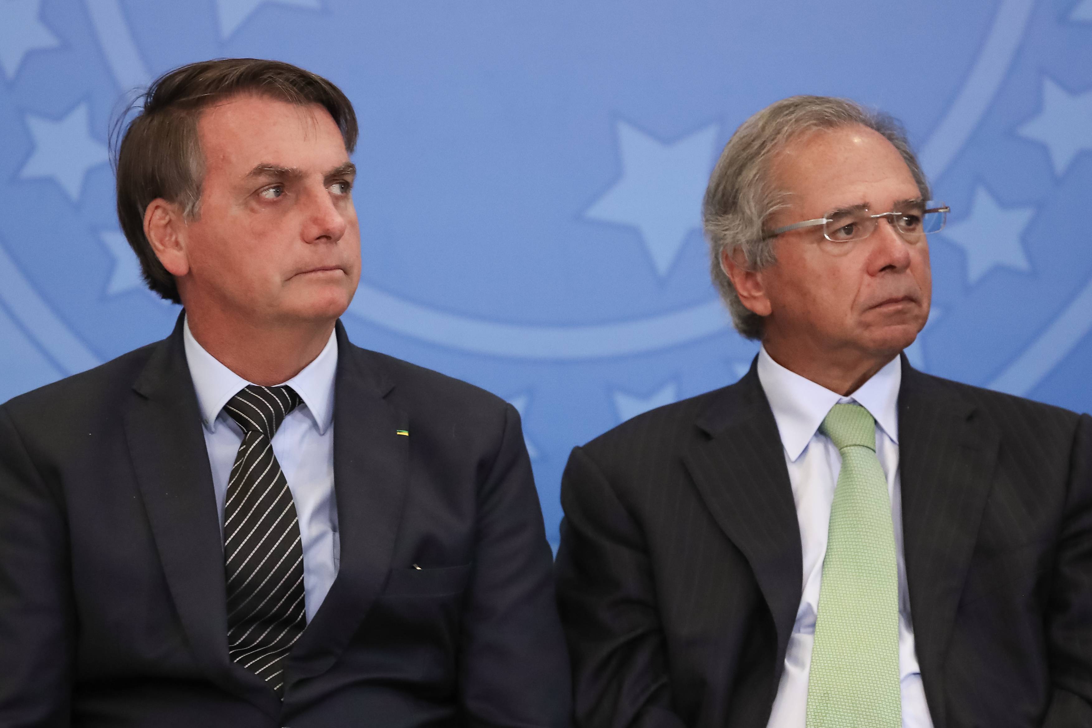 O presidente Jair Bolsonaro sentado ao lado do ministro da Economia, Paulo Guedes.