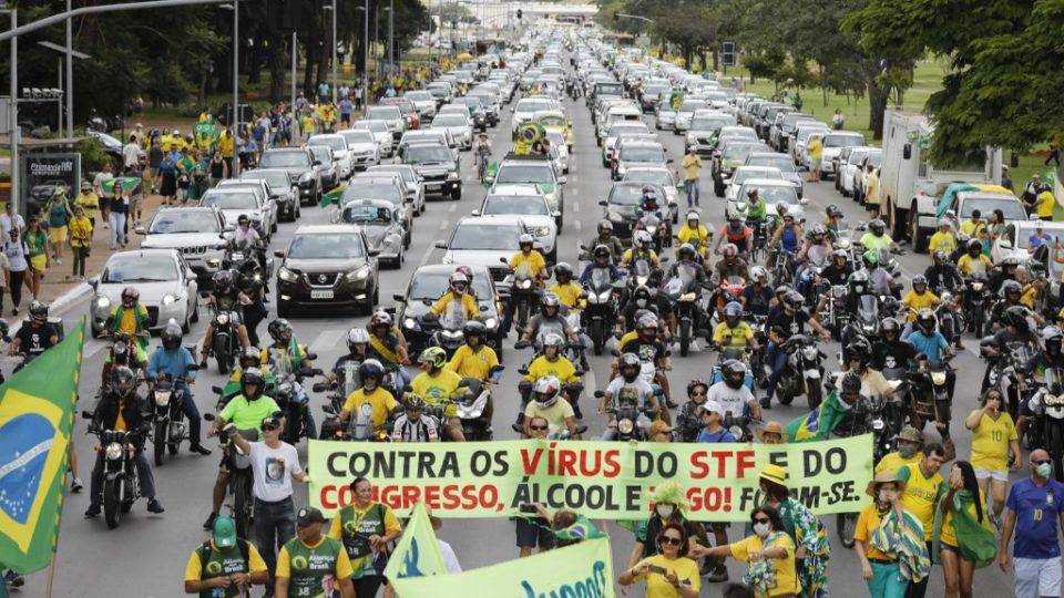 Manifestantes pró-Bolsonaro exibem bandeira contra o STF e o Congresso durante carreata em Brasília.