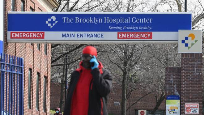 Homem usa máscara facial e luvas de proteção enquanto caminha pela ala de emergência do Brooklyn Hospital Center, em Nova York