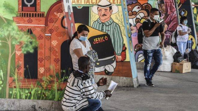 Pessoas usam máscara em terminal de ônibus de Medellín, na Colômbia.