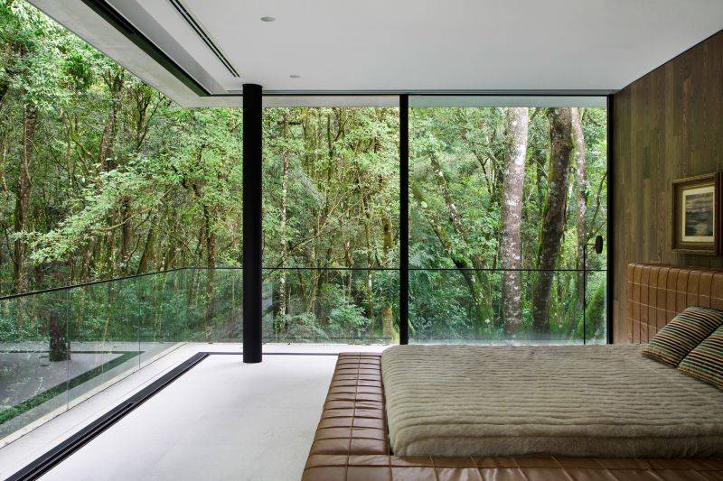 A parede de vidro do
quarto do casal permite
a contemplação das paisagens da natureza. Foto: MCA Estúdio A parede de vidro do
quarto do casal permite
a contemplação das paisagens da natureza. Foto: MCA Estúdio