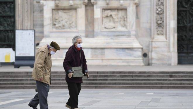 Casal caminha pela deserta praça Duomo, Milão, Itália, 31 de março de 2020, durante lockdown para conter a propagação da infecção do novo coronavírus