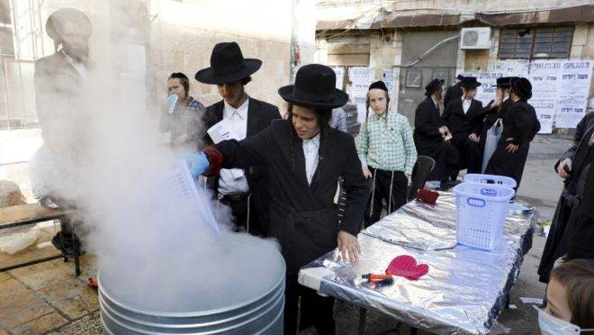 Judeus ultraortodoxos mergulham utensílios de cozinha em água fervente para purificá-los, em preparação antes da Pessach, feriado que celebra a libertação dos hebreus da escravidão no Egito. Jerusalém, 8 de abril de 2020