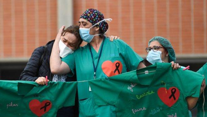 Profissionais de saúde dão apoio à esposa de um enfermeiro que morreu de Covid-19 em hospital na região de Madri, Espanha, 10 de abril. A Espanha registrou o menor número de mortos por coronavírus em 18 dias