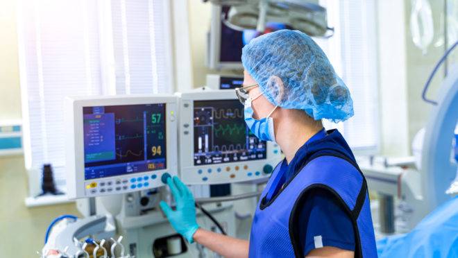 Enfermeira checa monitor de respirador artificial em Unidade de Terapia Intensiva.