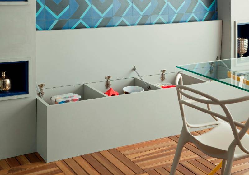 ). O banco abaixo dos ladrilhos hidráulicos é um suporte de mais lugares à mesa e de quebra guarda os brinquedos do filho do casal dono do apartamento ). O banco abaixo dos ladrilhos hidráulicos é um suporte de mais lugares à mesa e de quebra guarda os brinquedos do filho do casal dono do apartamento