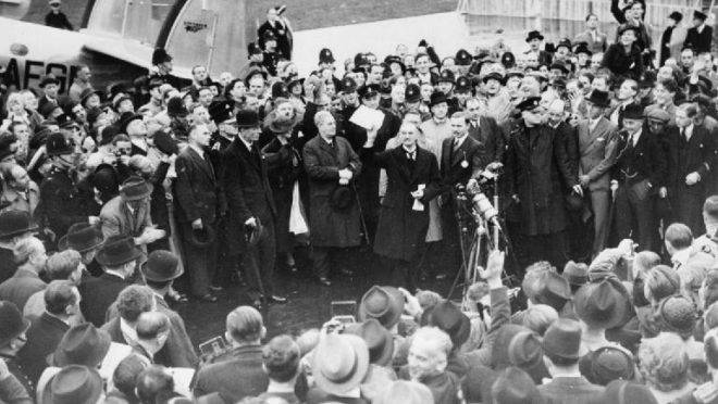 Neville Chamberlain exibe a resolução assinada por ele e Adolf Hitler em Munique, em aeroporto de Londres, 30 de setembro de 1938. “Teremos paz em nossos tempos”