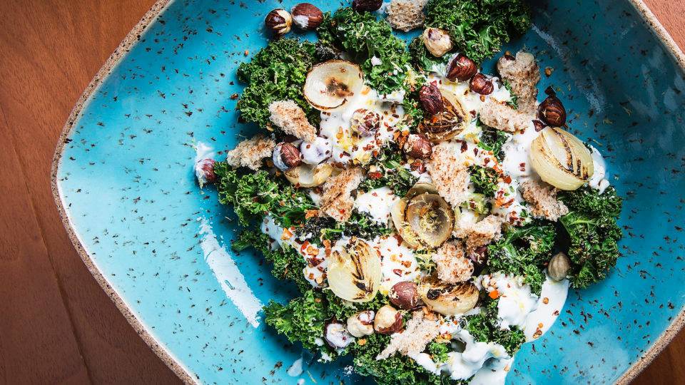 Salada morna de kale com molho de iogurte e avelãs tostadas