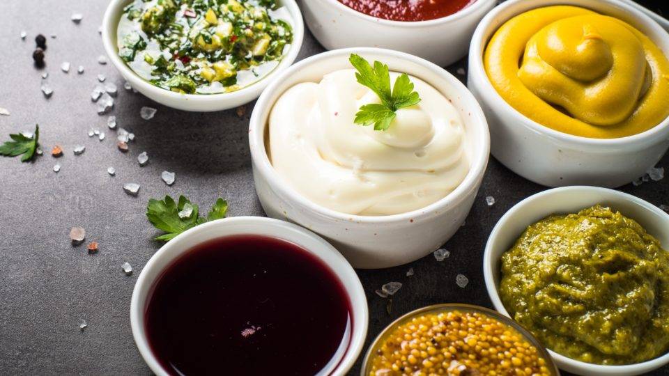 Chefs premiados ensinam como acertar no preparo de molhos Set of sauces – ketchup, mayonnaise, mustard soy sauce, bbq sauce, pesto, chimichurri, mustard grains and pomegranate sauce on dark stone background.